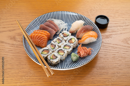 Mixed sushi meal on a blue Japanese ceramic plate, atop a wood table, 45-degree