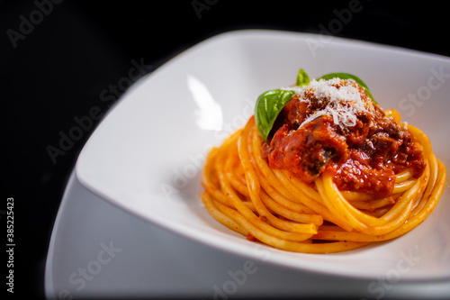 Spaghetti al sugo con formaggio e basilico fotografati in un piatto bianco