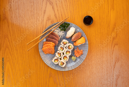 Sushi assortment on blue ceramic Japanese plate, top view on wood table