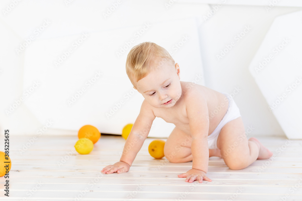 a small child a boy six months old plays on the floor in a bright white room in diapers with lemons and oranges a small child a boy six months old plays on the floor in a bright white room in diapers with lemons and oranges