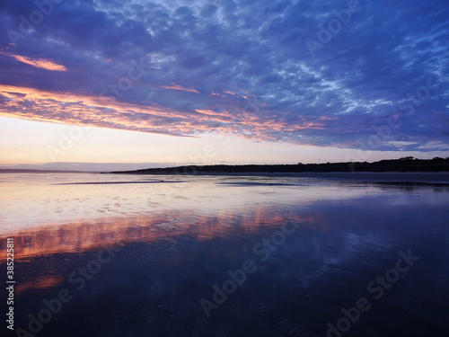 Fototapeta Naklejka Na Ścianę i Meble -  Dramatic sunset on Cefn Sidan beach with Cirrostratus clouds - is a long sandy beach, its dunes form the outer edge of the Pembrey Burrows between Burry Port and Kidwelly.