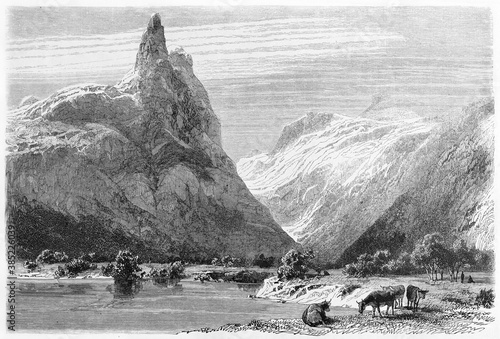 high mountains towering over Romsdalen valley with grazing cows, Norway. Ancient grey tone etching style art by Girardet, published on Le Tour du Monde, Paris, 1861 photo