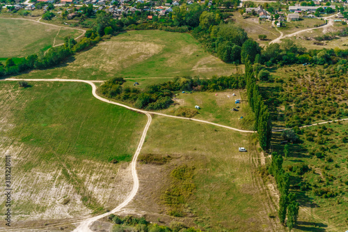 Top view of the dirt road with a crossroads and dense green forests and fields. Beautiful bright landscape photography on a summer day