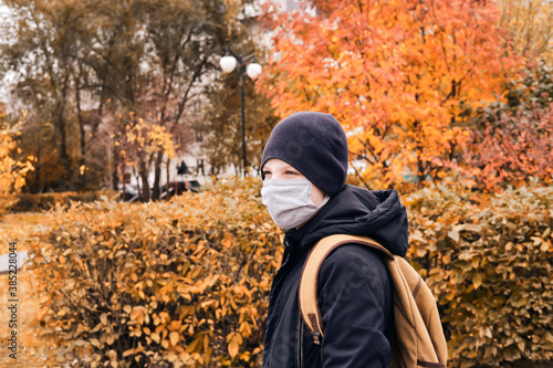 Schoolboy in a protective mask goes to school along an empty street.. New normal