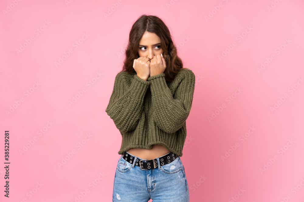 Young woman over isolated pink background nervous and scared putting hands to mouth Young woman over isolated pink background nervous and scared putting hands to mouth