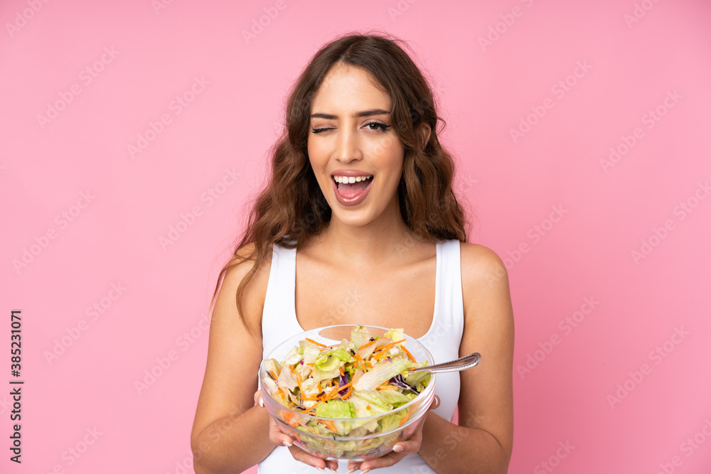 Young woman with salad over isolated pink wall Young woman with salad over isolated pink wall