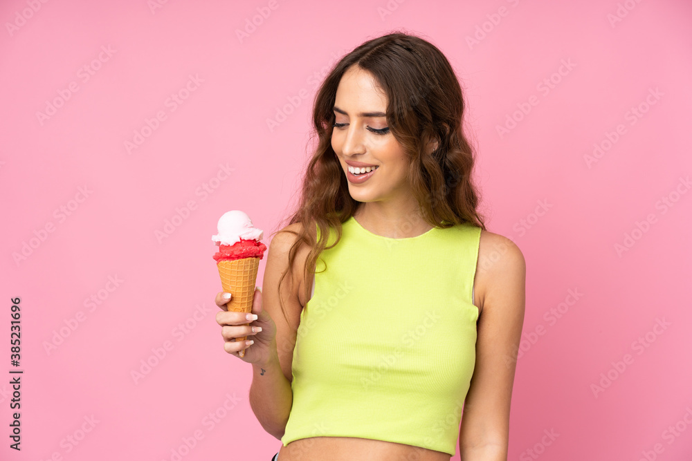 Young woman holding a cornet ice cream over isolated on a pink background with happy expression Young woman holding a cornet ice cream over isolated on a pink background with happy expression