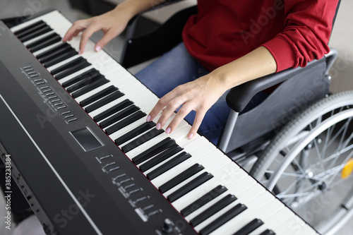 Woman in wheelchair plays synthesizer. Music lessons for people with disabilities concept