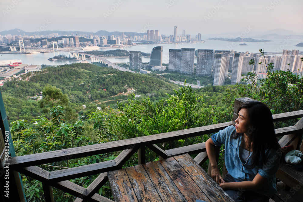 Asian girl watching a overview of the city from the top of the mountain