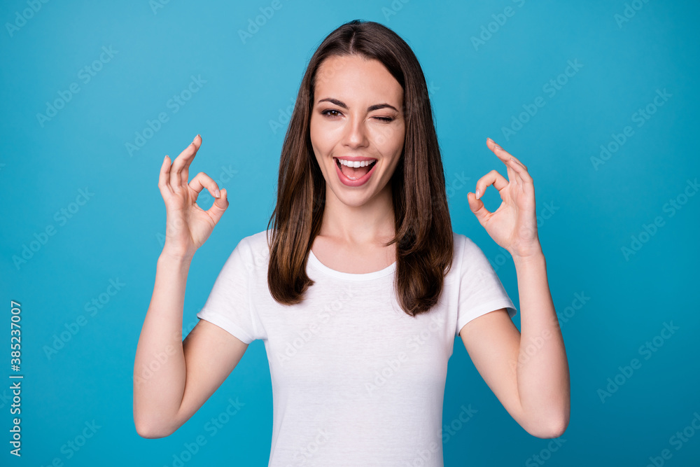 Portrait of excited girl show okay symbol recommend suggest select adverts promo wink blink wear good look outfit isolated over blue color background Portrait of excited girl show okay symbol recommend suggest select adverts promo wink blink wear good look outfit isolated over blue color background