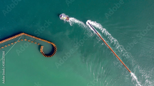 Aerial view of the boat during carry a long pile (stake) on the water to build pier (series-2). © Funtay