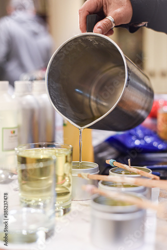 Creative occupation of candle making showing the pouring of liquid wax into jars