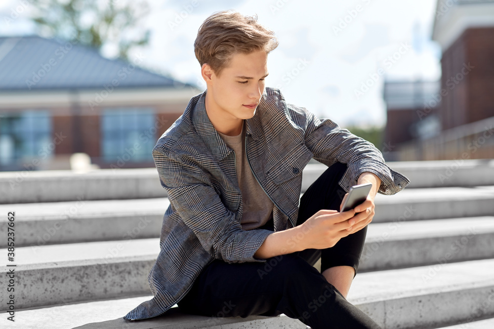 technology, communication and lifestyle concept - young man or teenage boy using smartphone in city technology, communication and lifestyle concept - young man or teenage boy using smartphone in city