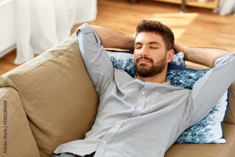 Fototapeta premium people and leisure concept - young man sleeping on sofa at home