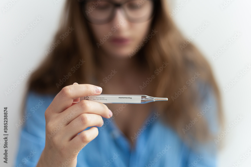 Close-up of medical fever thermometer being held by blonde woman showing high temperature. Virus disease outbreak. Close-up of medical fever thermometer being held by blonde woman showing high temperature. Virus disease outbreak.