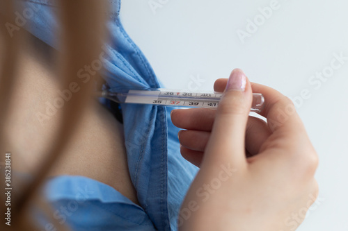 Blonde woman checking temperature with thermometer. Close-up. Coronavirus threat. White background.