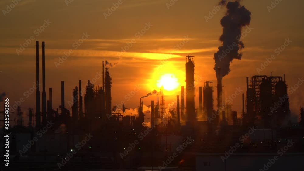 Smoking pipes of an oil refinery in the backlight of the sunset.
