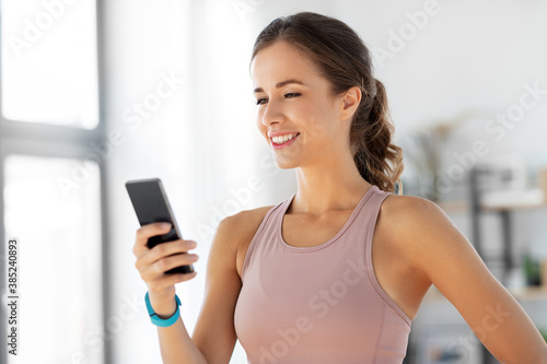 sport, fitness and technology concept - happy smiling young woman with smatphone exercising at home © Syda Productions