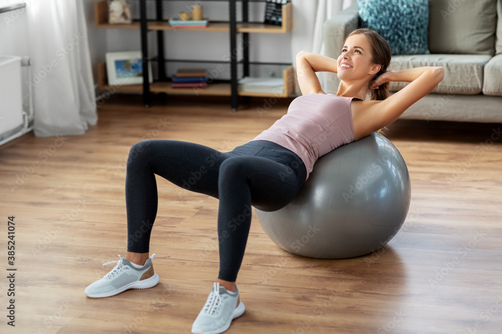 sport and healthy lifestyle concept - happy woman exercising on fitness ball at home sport and healthy lifestyle concept - happy woman exercising on fitness ball at home