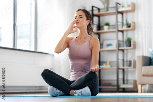 yoga, sport and healthy lifestyle concept - woman meditating in lotus pose at home © Syda Productions