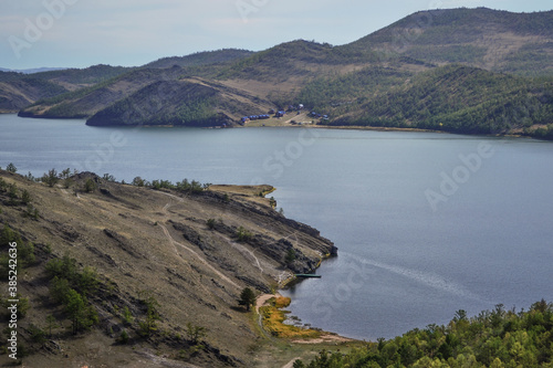 Autumn view of bay of Lake Baikal with peninsulas and mountains . Blue water, yellow and green trees. Landscape