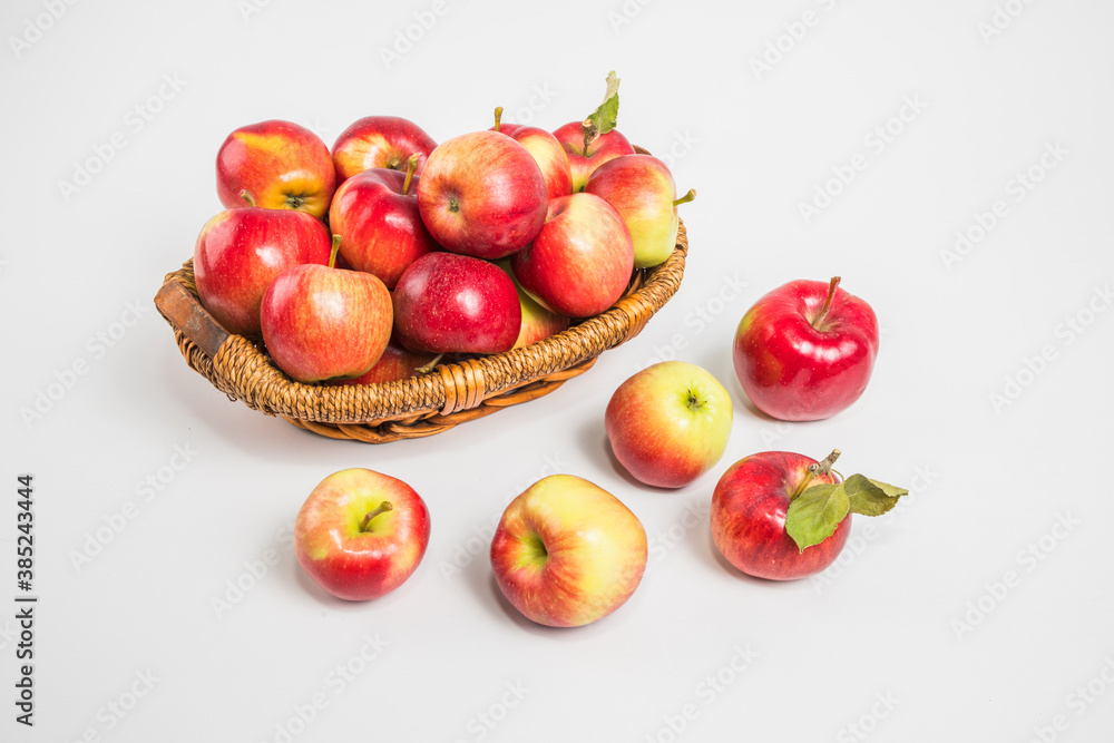 Bright multi-colored fresh apples in a wicker basket on a white background. Selective focus.