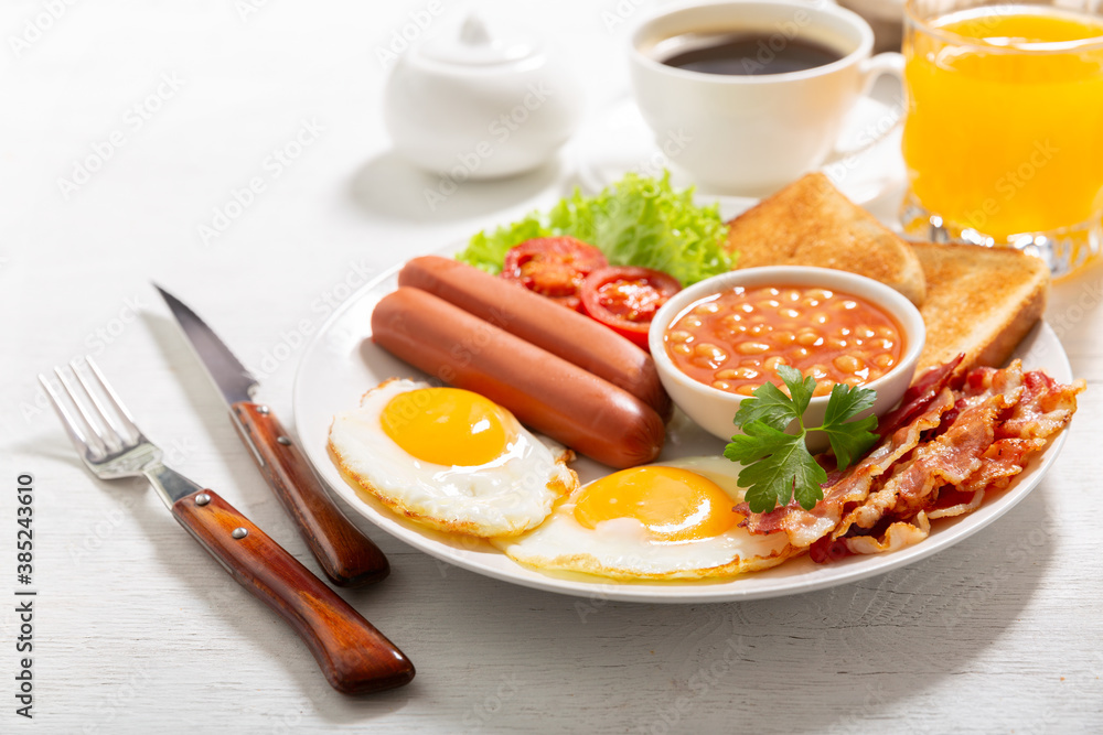 breakfast with plate of fried eggs, bacon, beans, sausages, toasts and tomatoes