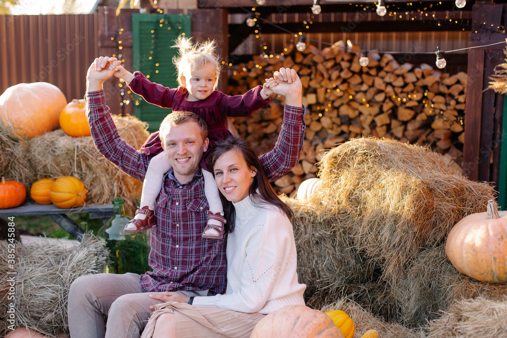 A young family celebrates Thanksgiving outside. Happy parents and child in country side harvest. Hello, Autumn! Festive mood. Preparing for halloween. Pumpkin decor. Togetherness Together. Positive