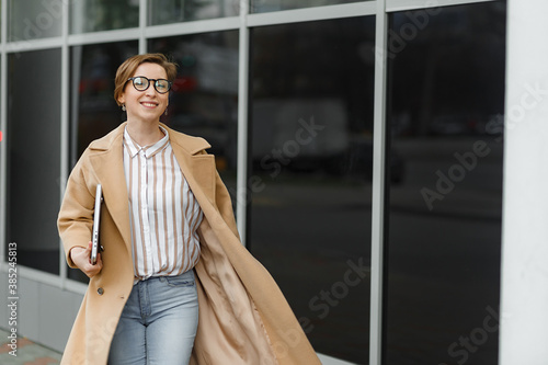 Young attractive girl with laptop walking  in the city