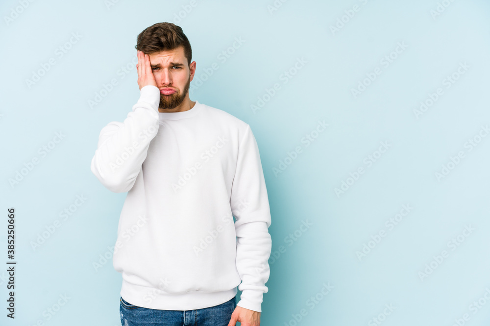 Young caucasian man isolated on blue background tired and very sleepy keeping hand on head. Young caucasian man isolated on blue background tired and very sleepy keeping hand on head.
