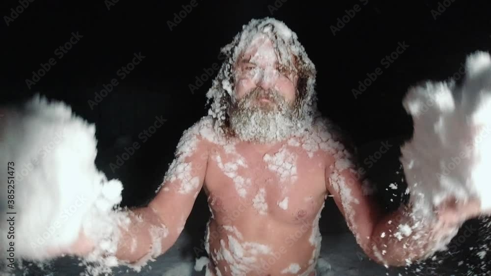 A naked man sits in a snowdrift and throws snow A naked man sits in a snowdrift and throws snow
