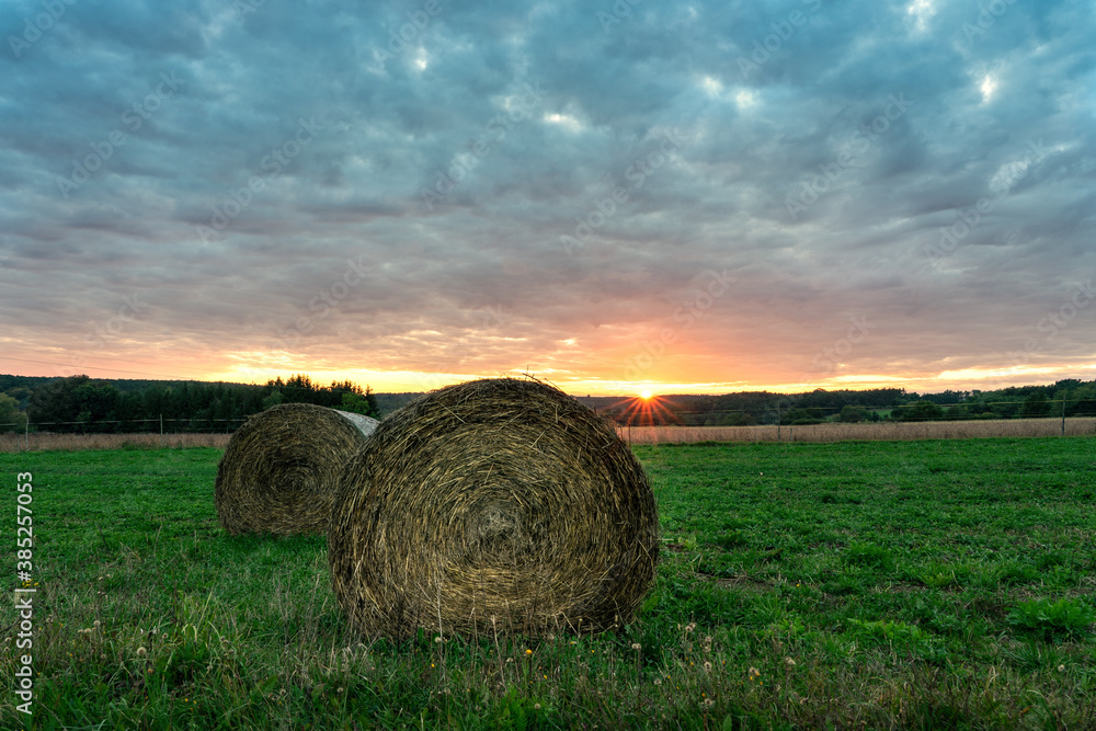 Beautiful sunset on the field in Őrség Hungary with sunbeams and bales