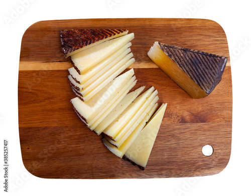 Slices of traditional spanish hard cheese Anejo from sheep milk on wooden surface. Isolated over white background