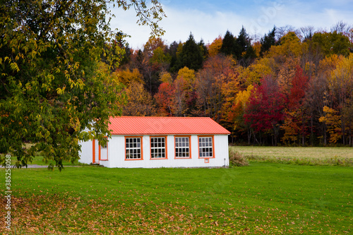 Small white and orange chicken coop against coloured trees and blue sky on the King’s Road, St-Augustin-de-Desmaures, Portneuf County, Quebec, Canada