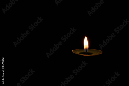 small burning candle on a dark background