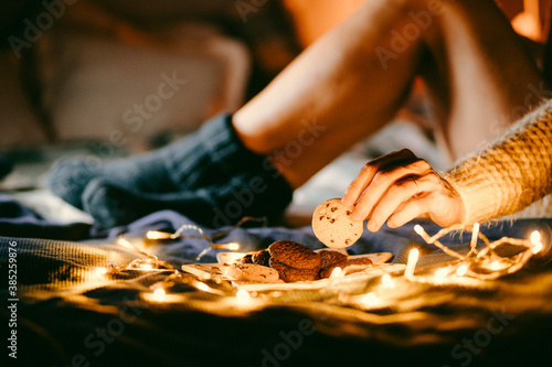 cozy Christmas at home woman in wool socks in bed eating cookies