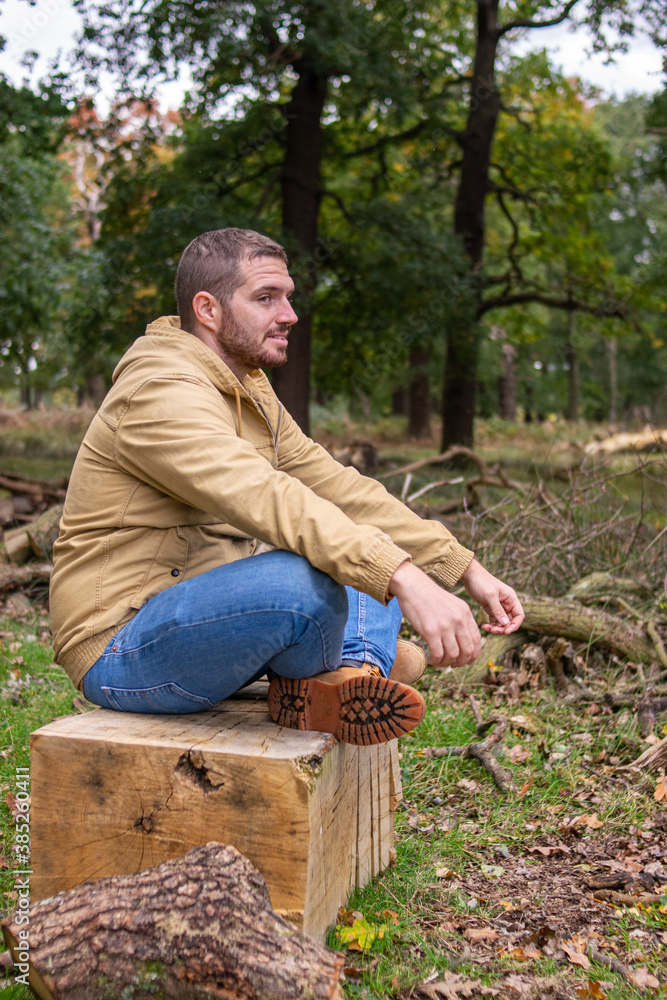 Photo of a young and attractive man sitting on a tree trunk practising meditation in the middle of nature. Self isolation in a forest. Relax Photo of a young and attractive man sitting on a tree trunk practising meditation in the middle of nature. Self isolation in a forest. Relax