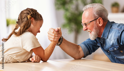 Grandfather arm wrestling with granddaughter. photo