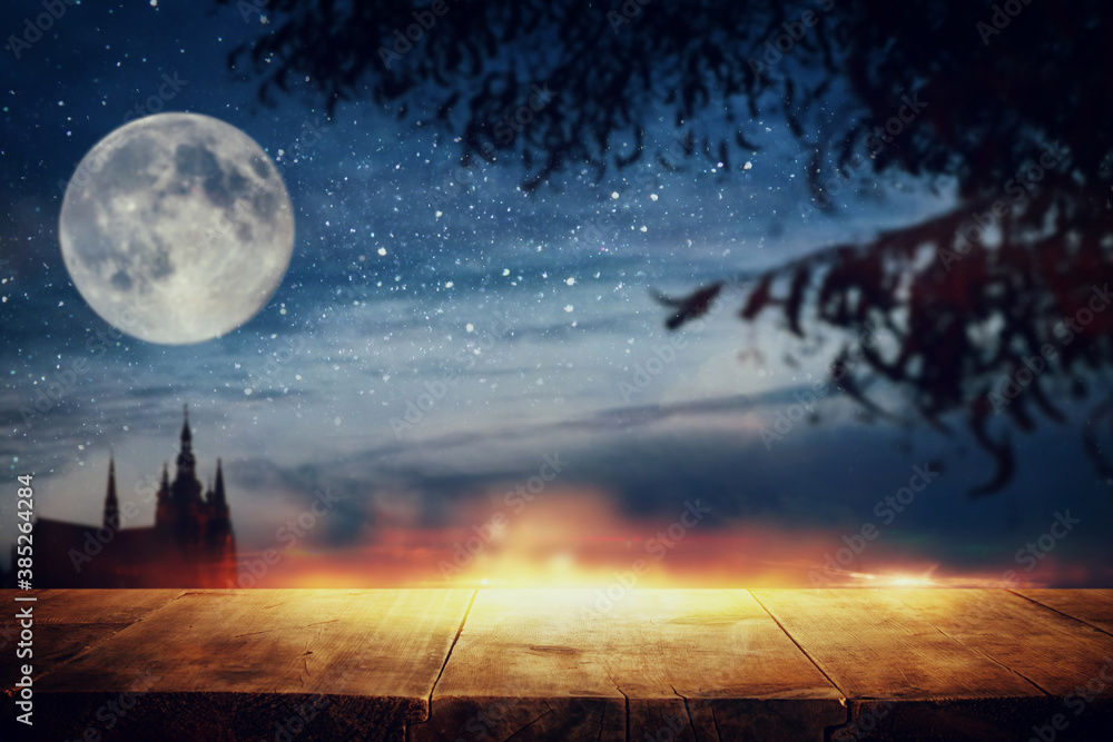 Halloween Holiday concept. Empty rustic table in front of scary and misty night sky, forest and full moon background. Ready for product display montage