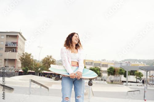 Beautiful girl at park holding a skateboard.