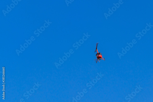 Flying orange helicopter in blue sky
