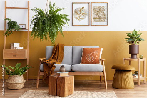 Stylish scandinavian interior of living room with design grey velvet sofa  cube  furniture  plants  carpet  decoration and mock up poster frames. Template.