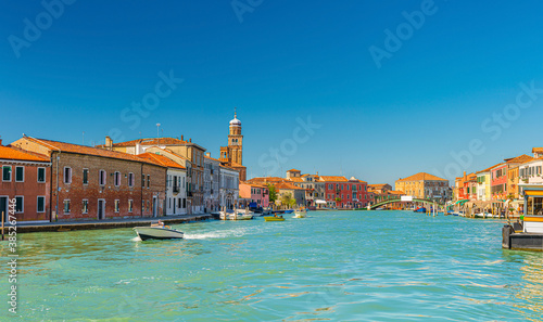 Murano islands with bridge across water canal, boats and motor boats, colorful traditional buildings, Venetian Lagoon, Province of Venice, Veneto Region, Northern Italy. Murano postcard cityscape. © Aliaksandr