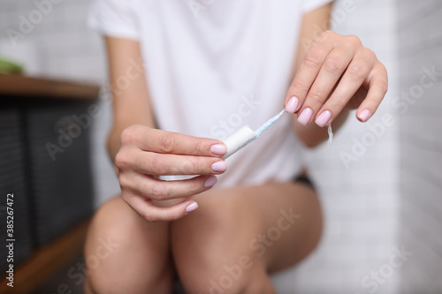 Woman sitting on toilet and holding a hygienic tampon in her hands Menstruation in women concept