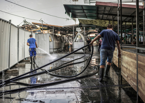 Workers washing green market pavement at the end of the work day