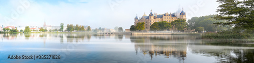 Schwerin panorama of the castle, bridge and town with reflection in the lake and morning fog, copy space