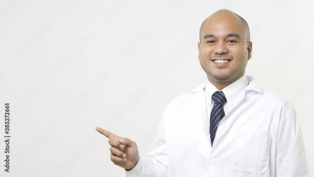 Young asian doctor in uniform pointing a finger to the side on isolated white background. 4K Resolution. Young asian doctor in uniform pointing a finger to the side on isolated white background. 4K Resolution.