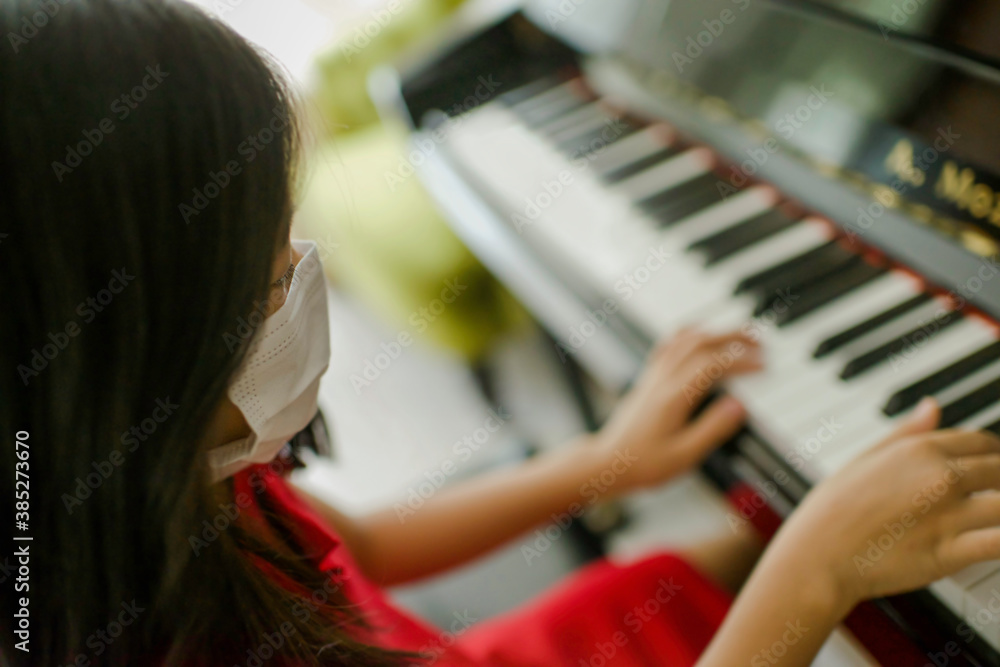 Pretty young musician playing upright piano at home during online class, social distance during quarantine, self-isolation, online education concept.Female Asian plays instrument. Pretty young musician playing upright piano at home during online class, social distance during quarantine, self-isolation, online education concept.Female Asian plays instrument.
