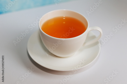 White cup of tea and saucer on blue background.Blue coffee cup on the white table over blue grunge background