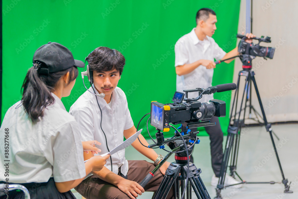Asian Students on Media studies course in broadcast television green screen studio room with Cameraman working in studio. Selective Focus Asian Students on Media studies course in broadcast television green screen studio room with Cameraman working in studio. Selective Focus